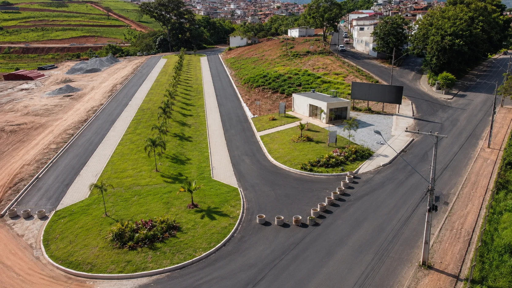 Vista aérea da rotatória de acesso, vias asfaltadas e paisagismo do Serra Verde Bairro Planejado.